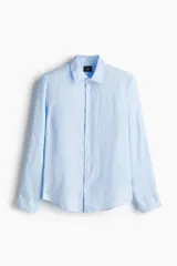 Camisa de lino liviano color celeste, con cuello italiano, tapeta lisa y canesú en la espalda. Tiene mangas largas con tapeta y botón, puños abotonados y bajo redondeado. Presenta un corte ajustado.