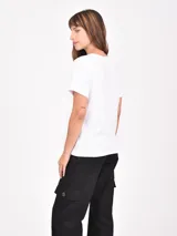 Remera blanca de manga corta con cuello redondo y un estampado frontal de un jarrón azul a rayas con flores rosadas.