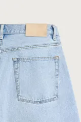 Bermuda de jean con corte holgado y pierna recta, confeccionada en denim de algodón rígido con efecto lavado. Presenta diseño clásico de cinco bolsillos y cierre frontal con botones.