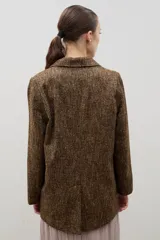 Blazer de lana con diseño bicolor, cuerpo en color negro y mangas en color crema. Presenta un corte holgado, cierre cruzado con doble botonadura y solapas amplias en contraste.