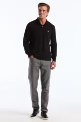 Polo de manga larga color negro, con cuello polo y tapeta de dos botones blancos. Presenta un pequeño logo bordado de pingüino en el pecho.