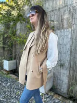 Chaleco color beige con cuello solapa, doble botonadura y lazo para atar en la cintura.