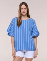 Blusa de corte cuadrado y silueta amplia, color azul con diseño de rayas verticales en tonos más claros. Cuenta con cuello redondo y mangas cortas acampanadas, decoradas con una hilera de botones de madera sobre los hombros.
