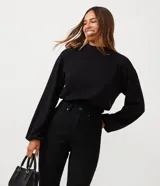 Blusa cropped de ribana negra con cuello alto, mangas largas y barra con elástico.