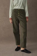 Pantalón de corderoy en color verde oliva, con corte tipo barrel de tiro alto y cierre frontal con botones metálicos dorados.