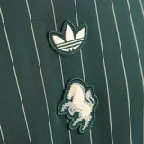 Camiseta de punto oversized verde oscuro de la colección Icons de Adidas, inspirada en los años 80, con rayas diplomáticas blancas, las icónicas tres tiras de la marca en las mangas, cuello redondo y el logotipo del trébol bordado junto al escudo vintage de la Juventus.