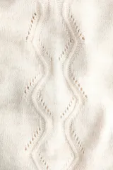 Pantalón de punto suave color beige, de tiro alto con cintura elástica, perneras rectas, secciones laterales con diseño pointelle y detalle de volados en el bajo.