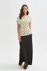 Top de poliéster negro con estampado de lunares blancos, diseño al cuerpo y cuello asimétrico de manga corta.
