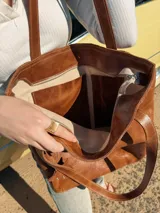 Bolso shopper de cuero color marrón con asas al hombro y dije colgante en forma de búho.