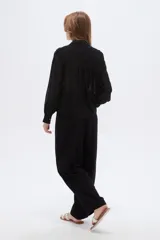 Camisa negra de poliéster con detalles de lurex y textura en relieve, corte holgado, mangas largas con puños y cierre frontal con botones.