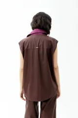 Chaleco marrón de cuerina con cuello de pana color lila, con bolsillos frontales y cierre con botones.
