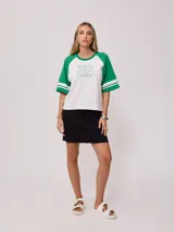 Remera bicolor Rusty con cuerpo verde lima y mangas ranglán grises con dos rayas blancas en los puños. Estampado frontal con el logo de la marca y el número 85.