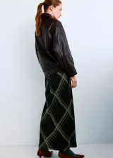 Chaqueta oversize de piel de ovino marrón oscuro, con cuello camisero, cierre frontal de cremallera y botones a presión ocultos bajo tapeta, bolsillos frontales de ribete y bajo elástico fruncido.