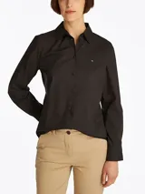 Camisa negra de popelín de mezcla de algodón elástico, corte regular, cuello inglés y puños con botón. Presenta el logo de Tommy Hilfiger bordado en el pecho.