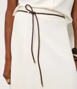 Pollera midi evasê color blanco, confeccionada en viscolino, con cintura alta y cinturón fino negro desmontable.