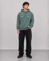 Canguro con capucha de color verde con efecto lavado, diseño de corte holgado, bolsillo frontal tipo canguro, cordones ajustables y logo estampado en el pecho.