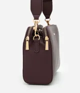 Cartera bandolera de tamaño mediano en cuero sintético color bordó, con formato rectangular y múltiples compartimentos con cierre de cremallera. Incluye correa de hombro ajustable en grosgrain y herrajes metálicos dorados.