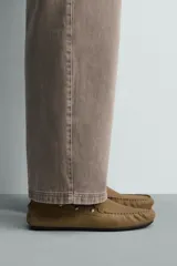 Mocasín de vestir para hombre confeccionado en piel con acabado de serraje en color mostaza. Presenta un diseño de horma redonda con detalle de tachas metálicas en los laterales y suela de goma flexible.