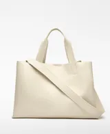 Bolso shopper horizontal negro de piel sintética, con dos compartimentos, cierre magnético y bolsillo interior con cremallera. Cuenta con asa de mano y correa larga regulable y extraíble, además del logo grabado en el frente.