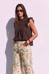 Blusa sin mangas de color crudo, con diseño oversize, cuello redondo y detalles de nido de abeja bordado en el pecho, acompañado de volados en los hombros.