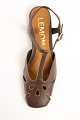 Sandalias planas de cuero marrón, con diseño calado en la puntera, tira en T y tira ajustable al tobillo con hebilla metálica dorada.