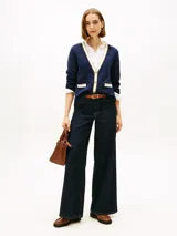 Cárdigan de punto azul marino con cuello en V, cierre frontal con botones dorados y bolsillos delanteros con ribetes en contraste. Presenta detalles en lurex en el cuello y los bolsillos, y logo de la marca bordado en el pecho.