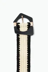 Cinturón de rafia color crudo con borde negro y hebilla geométrica negra con detalles dorados.