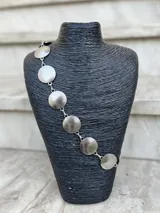 Cinto plateado de metal con eslabones y monedas circulares con textura. Tiene cadena regulable.