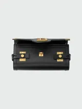 Clutch Balmain modelo B-Buzz, confeccionado en cuero negro con herrajes metálicos dorados. Presenta un diseño estructurado con cierre frontal tipo solapa, logo B metálico y detalles de correas laterales con broches grabados.