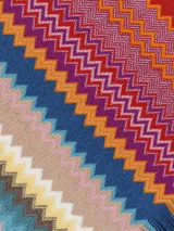Chal tipo bufanda de punto con diseño de zigzag multicolor, característico de Missoni. Presenta un borde rojo sólido y flecos en los extremos.