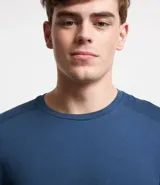 Remera deportiva de hombre con tecnología dry fit, cuello redondo y manga corta. Presenta un diseño liso en color beige con una pequeña etiqueta decorativa en el dobladillo.