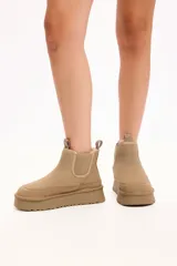 Bota tipo chelsea de gamuza color camel, con interior forrado en piel sintética, elásticos laterales y plataforma alta con suela dentada.