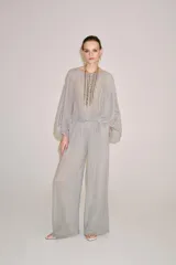 Pantalón palazzo gris de tejido semitransparente con tiro medio, cintura elástica, bolsillos laterales y forro interior corto.