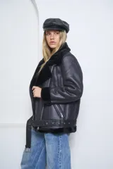 Campera tipo gamulán de cuero sintético negro con interior de corderito sintético al tono. Presenta cierre frontal diagonal, cuello amplio con solapas, bolsillos laterales con cierre y detalles de corderito en puños y ruedo.