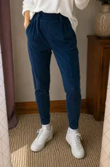 Pantalón agamuzado de color azul marino, de corte chupín con cintura elástica fruncida y costuras frontales marcadas.