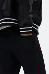 Pantalón jogger negro de corte relajado, con cordón ajustable en la cintura, franjas laterales rojas y estampado con la palabra "Honda" en la pierna izquierda.