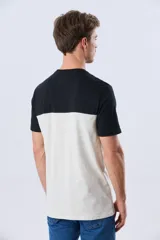 Remera de algodón y poliéster de corte clásico, con diseño en bloques de color negro en la parte superior y gris melange en la inferior. Presenta cuello redondo, mangas cortas y un pequeño estampado tipográfico en el pecho.