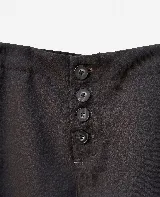 Pantalón sastrero de tiro bajo con calce relajado, confeccionado en pana. Presenta cierre frontal con botones visibles y bolsillos laterales.
