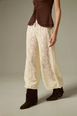 Pantalón tipo babucha de encaje color crudo, con corte holgado y cintura elástica.