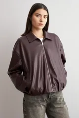 Chaqueta bomber de eco cuero en color bordó, con cierre frontal metálico y cuello clásico. Presenta un diseño de corte recto y mangas largas.