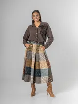 Falda midi de paño con estampa patchwork de inspiración escocesa, confeccionada en mezcla de lana. Presenta pinzas frontales, cintura elástica para mayor comodidad y un cinto desmontable a tono.