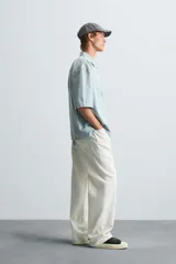 Camisa de corte relajado confeccionada en tejido de algodón, con estampado de cuadros pequeños en tonos celestes y blancos. Presenta cuello solapa, manga corta y bolsillo plastrón en el pecho con cierre frontal de botones.