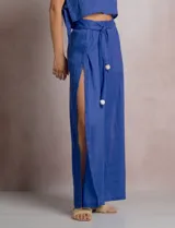 Pantalón palazzo de lino color azul, de tiro alto con cintura elastizada y cinto lazo incorporado con cuentas decorativas en las puntas. Presenta aberturas laterales pronunciadas en las piernas y corte amplio.