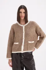 Saco tipo cardigan de tejido bouclé en color visón, con bordes y detalles en color crema. Presenta cuello redondo, cierre frontal con botones y dos bolsillos delanteros con solapa.