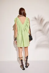 Minivestido beige con escote en V, breteles con lazos y corte holgado.
