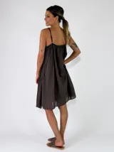 Vestido midi de tirantes color marrón oscuro, con diseño fluido, escote en V fruncido y detalles de terminación desflecada.