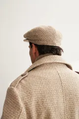 Boina con visera de lana fina uruguaya natural, sin teñir, con diseño de tejido texturizado en tonos beige y marrón.