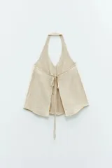 Top color beige claro, sin mangas, con tiras finas hacia el cuello y espalda descubierta que se cierra con dos lazos ajustables.