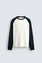 Camiseta de manga larga con estructura waffle, corte regular fit. El cuerpo es de color blanco crudo y las mangas raglán son de color azul marino. Tiene cuello redondo a contraste.