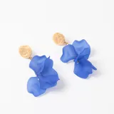 Caravanas colgantes con base circular de metal dorado texturizado y pétalos de resina en color azul intenso.